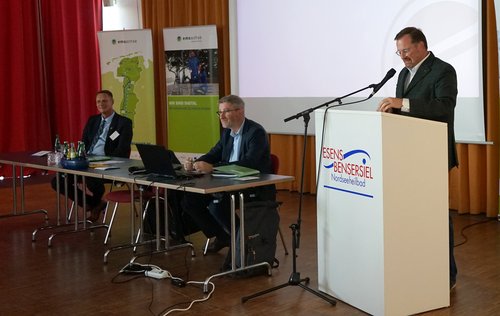 Holger Heymann (Landrat des Landkreises Wittmund), Dr. Dirk Lüerßen (Geschäftsführer der Ems-Achse) und Bernard Krone (Vorstandsvorsitzender der Ems-Achse) (von links) führen durch die Mitgliederversammlung.