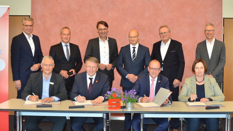 Bei der Vertragsunterzeichnung (sitzend von links): David Ostholthoff (Bürgermeister Hörstel und stellvertretender Zweckverbandsvorsteher der Kreissparkasse), Gregor Krabbe (Bürgermeister Metelen und Zweckverbandsvorsteher der Kreissparkasse), Oliver Kellner (Bürgermeister Emsdetten und Verwaltungsratsvorsitzender der Verbundsparkasse) und Christa Lenderich (Bürgermeisterin Ochtrup und Zweckverbandsvorsitzende der Verbundsparkasse); (stehend von links): Carl-Christian Kamp (Vorstand Kreissparkasse), Dr. Peter Eckhardt (Vorstandsvorsitzender der Verbundsparkasse), Rainer Langkamp (Vorstandsvorsitzender der Kreissparkasse), Dr. Martin Sommer (Landrat und Verwaltungsratsvorsitzender der Kreissparkasse), Rainer Lammers (Bürgermeister Lotte und Zweckverbandsvorsitzender der Kreissparkasse) und Peter Hensmann (Vorstand Verbundsparkasse)